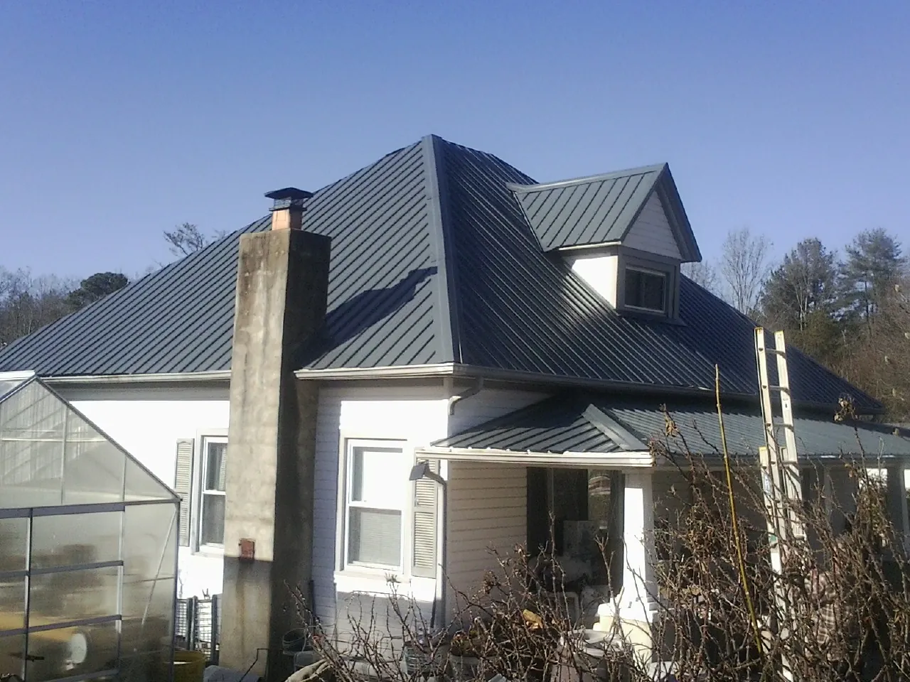 Dark blue standing seam metal roof on a white farmhouse with dormer — Slate & Tile Roof Repair by Roofing Brothers in Beckley