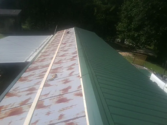 Old rusted panels beside newly installed green metal roofing — Wind Damage Roof Repair by Roofing Brothers in Beckley