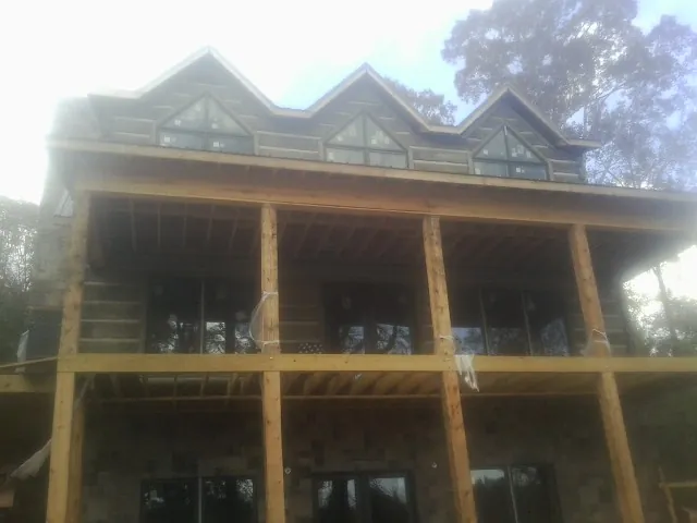 Dormers and porch framing on a large log home under construction — Roof Coating work by our crew in Beckley