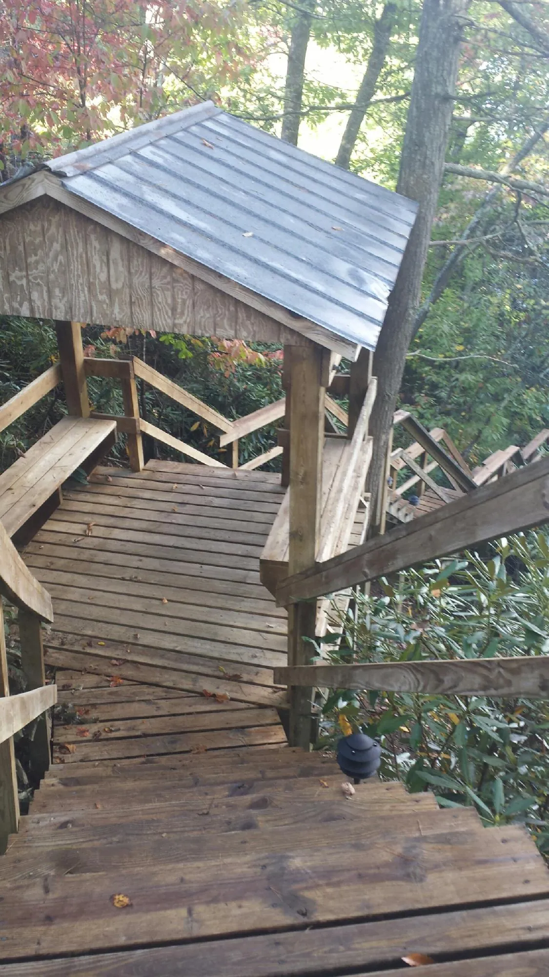 Metal roofed shelter over wooden steps on a wooded walkway — Skylight Repair & Installation work by our crew in Beckley