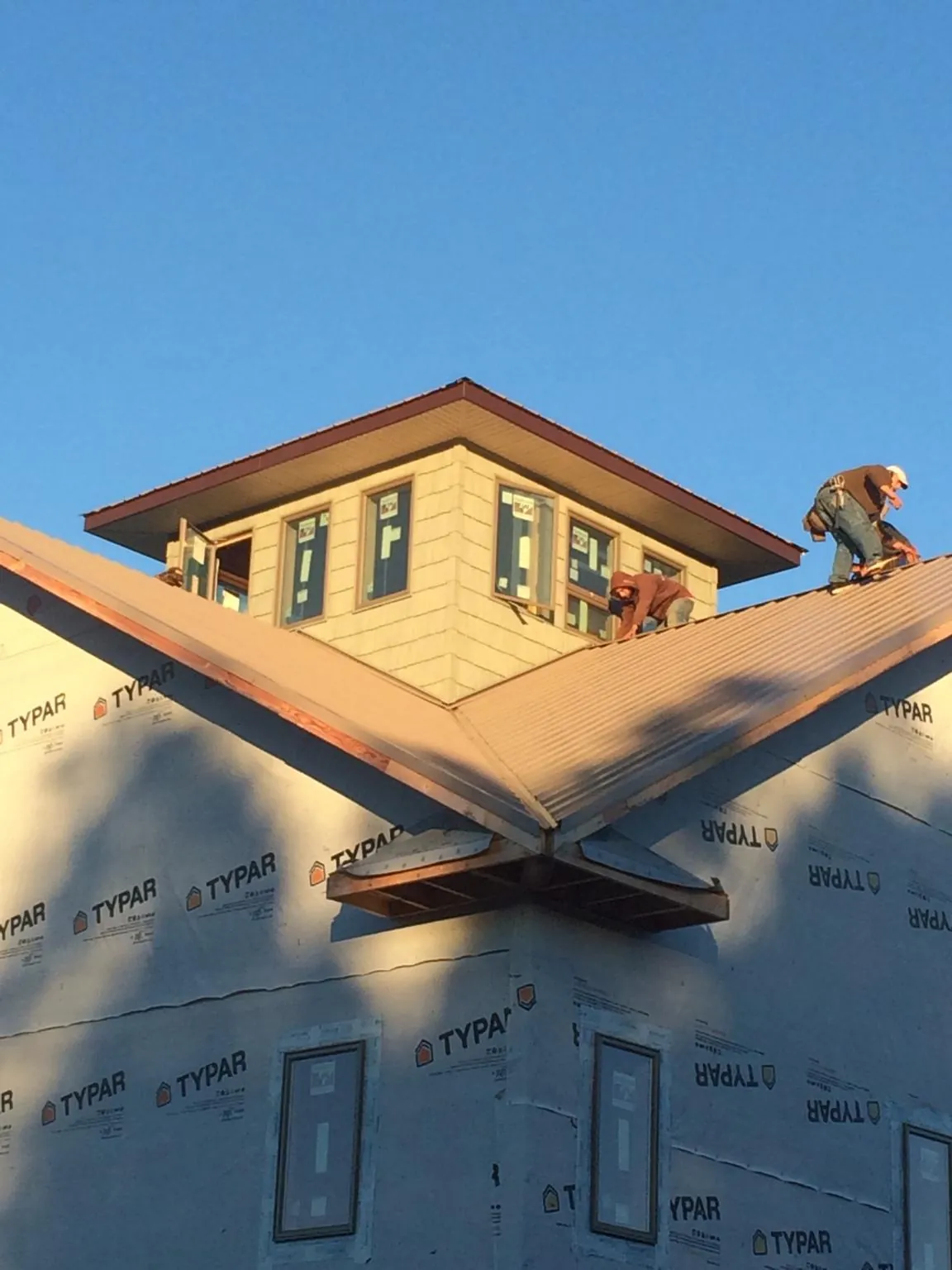 Roofers working around a rooftop cupola on a new metal roof at sunset — Roof Waterproofing in Beckley by Roofing Brothers